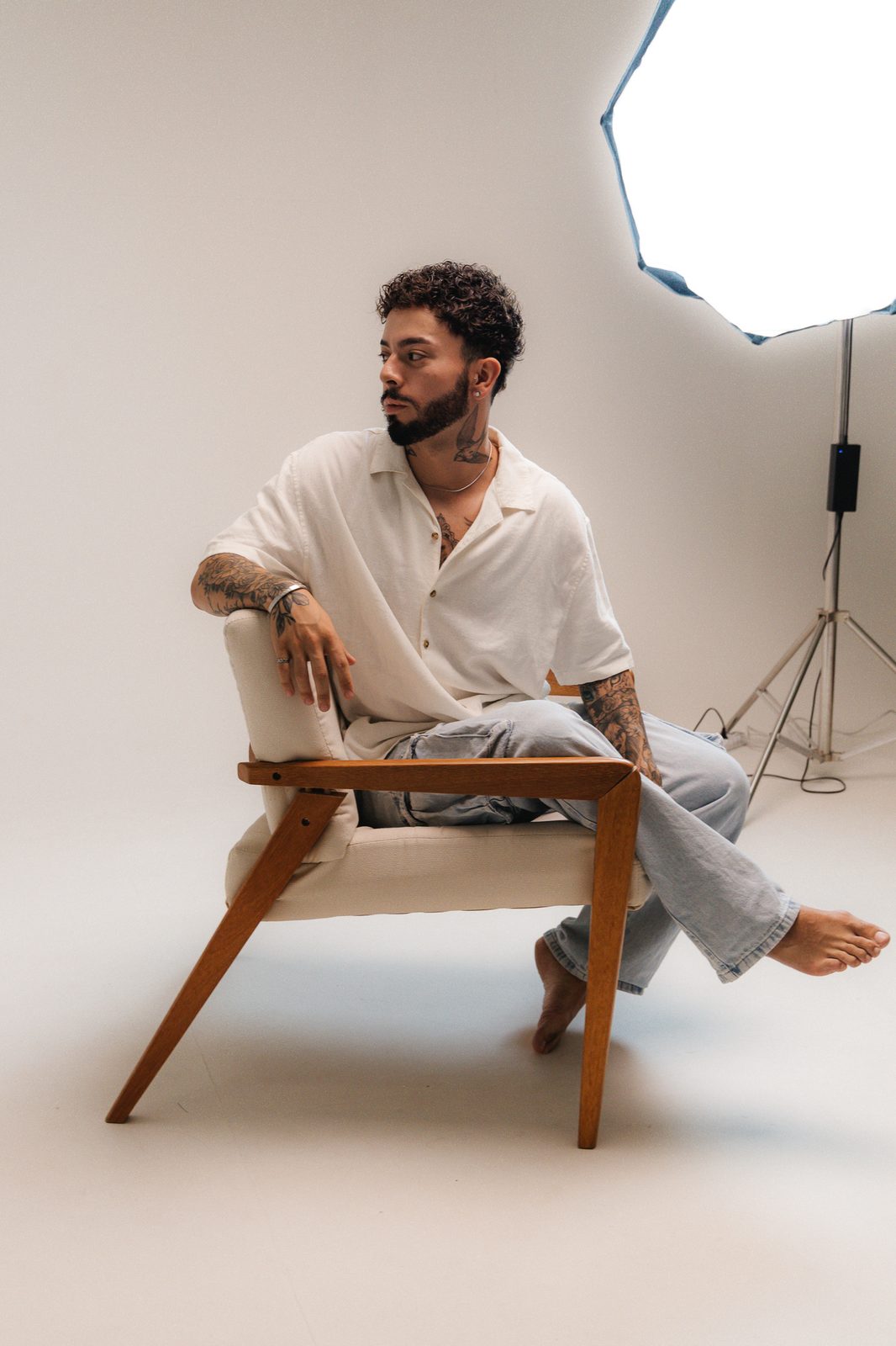 Jon, do Coala Criativo, sentado numa poltrona de linho em um estúdio fotográfico