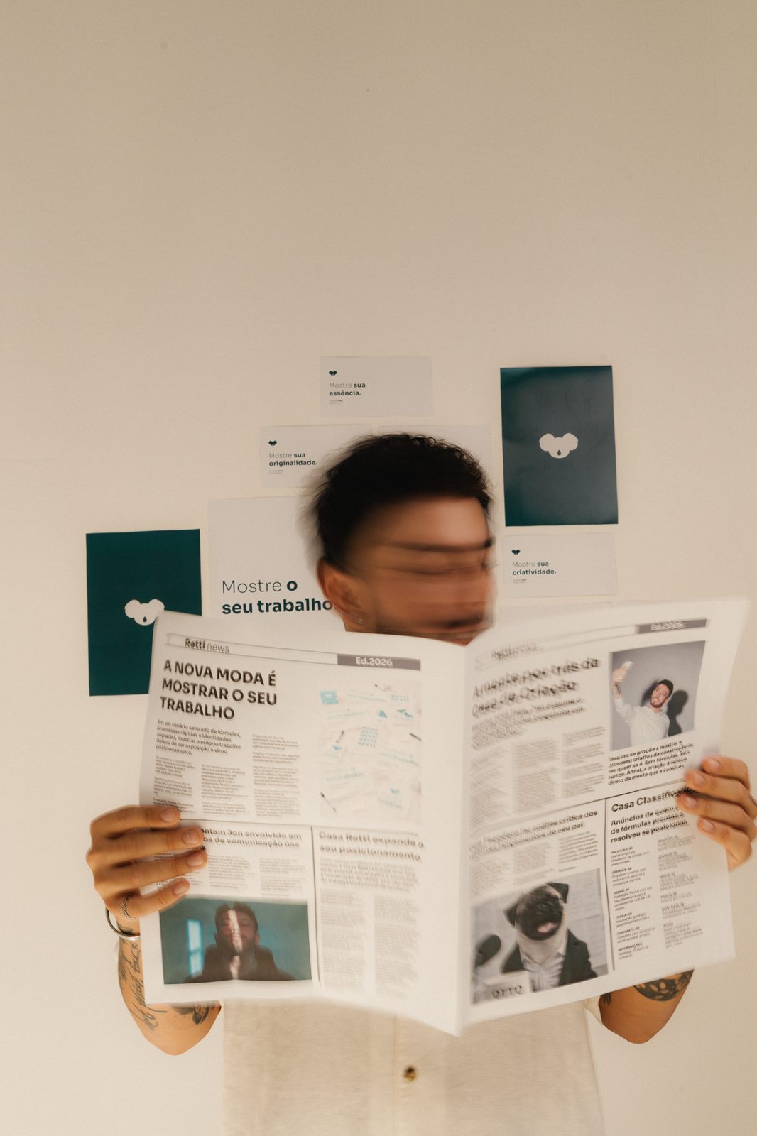Jon lendo um jornal com a manchete 'A nova moda é mostrar o seu trabalho'